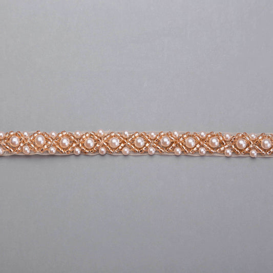 Pärlband Nora Rose med roségyllene strass och vita pärlor i X-mönster — närbild