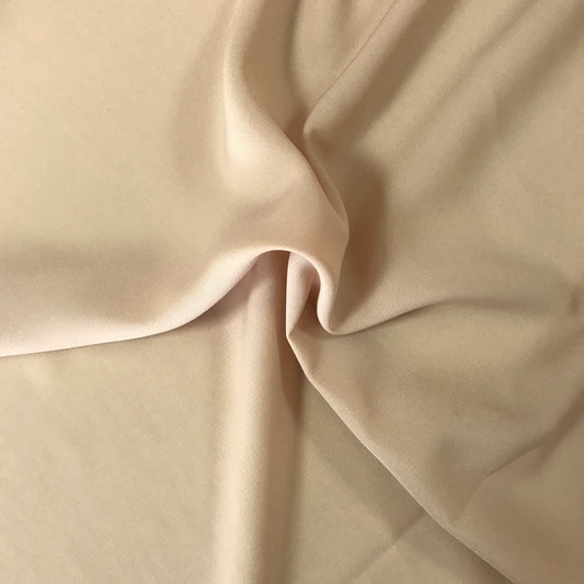 Crepetyg ljusbeige visat som elegant blus med rynkad halsringning, mjukt flödande