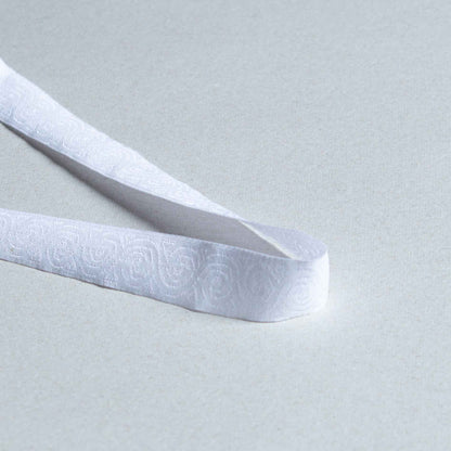 Tygband i vitt med diskret präglat cirkelmönster och spiraldetaljer